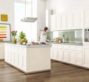 sunlit white wood kitchen with woman cutting vegetables